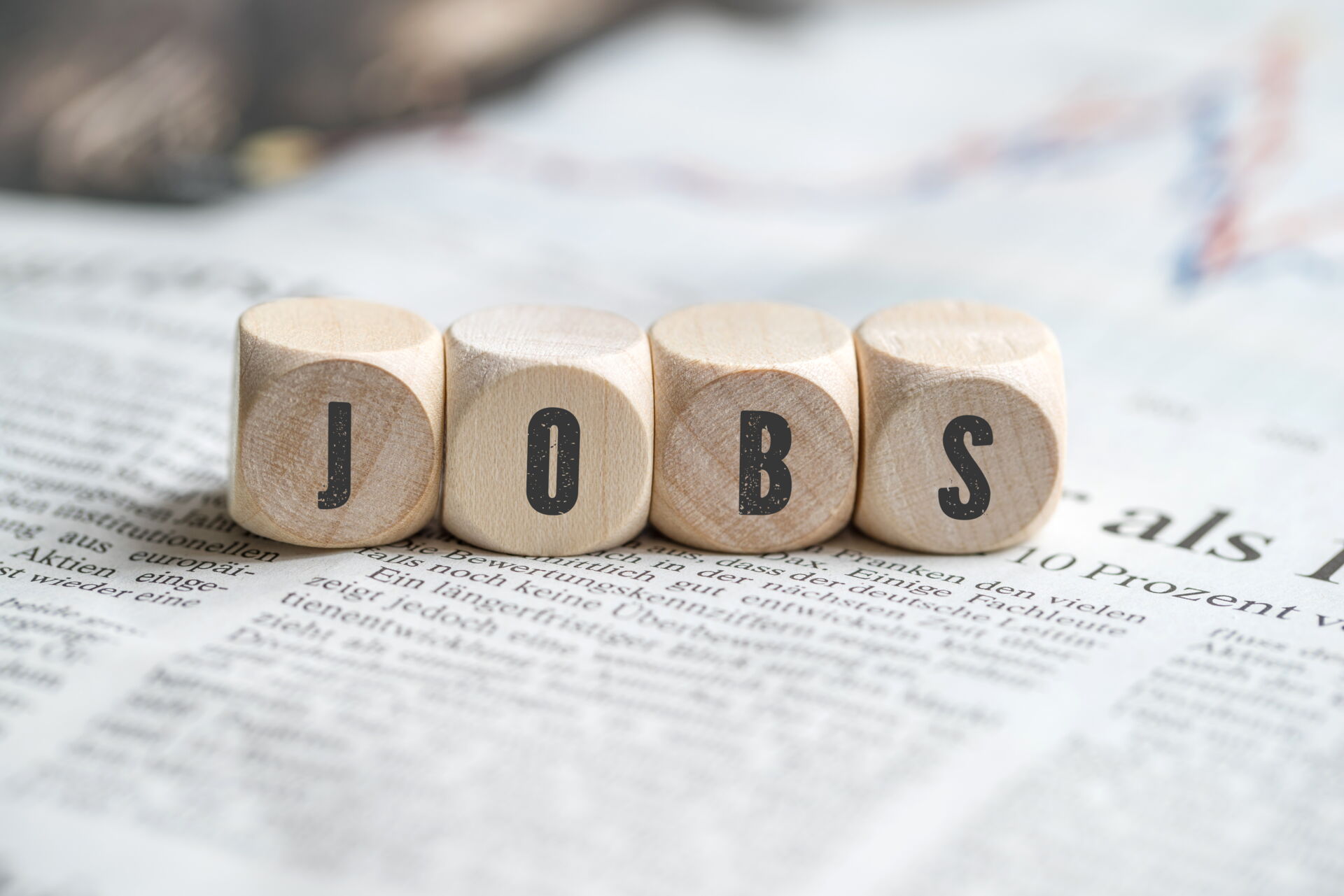 Holzwürfel bilden das Wort "JOBS" auf einer Zeitungsseite. Stellenangebote beim Elektro Bohr Handwerksbetrieb.