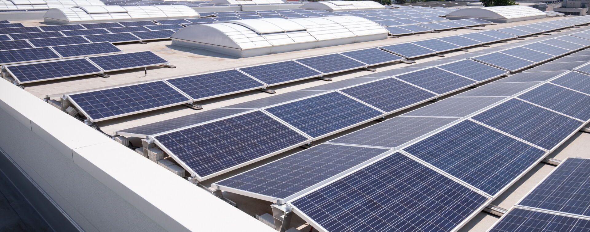 Eine große Solaranlage auf einem Flachdach mit mehreren Reihen von Solarmodulen. Elektro Bohr in Saalfeld.